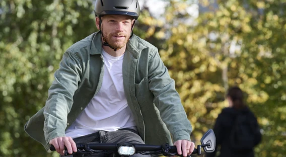 Ein Mann mit Helm fährt auf einem Fahrrad durch eine grüne Umgebung, während er nach vorne schaut.