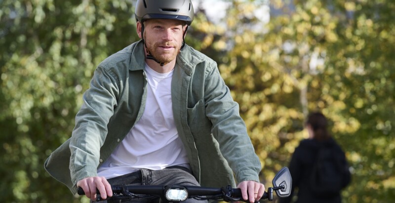 Ein Mann mit Helm fährt auf einem Fahrrad durch eine grüne Umgebung, während er nach vorne schaut.